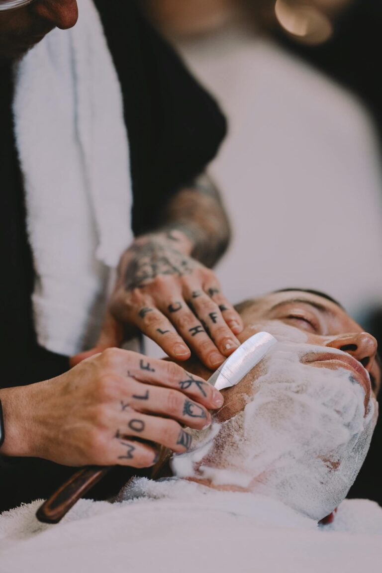 Barber expertly shaves a client's beard with precision and care in a modern barbershop.